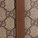 GG canvas with brown leather trim and visible edge stitching on dome bag