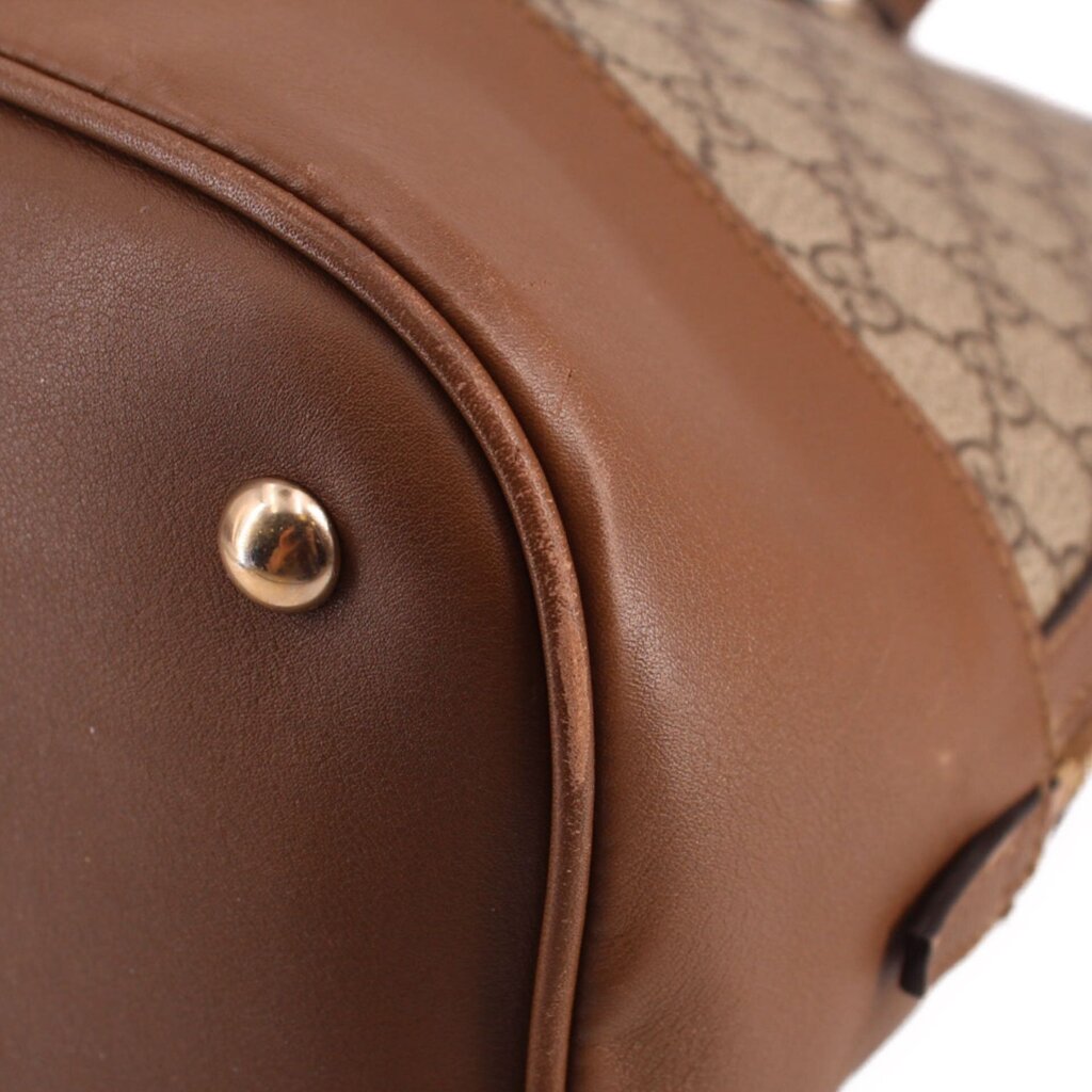 Brown leather side panel with gold-tone rivet and GG canvas trim on bag