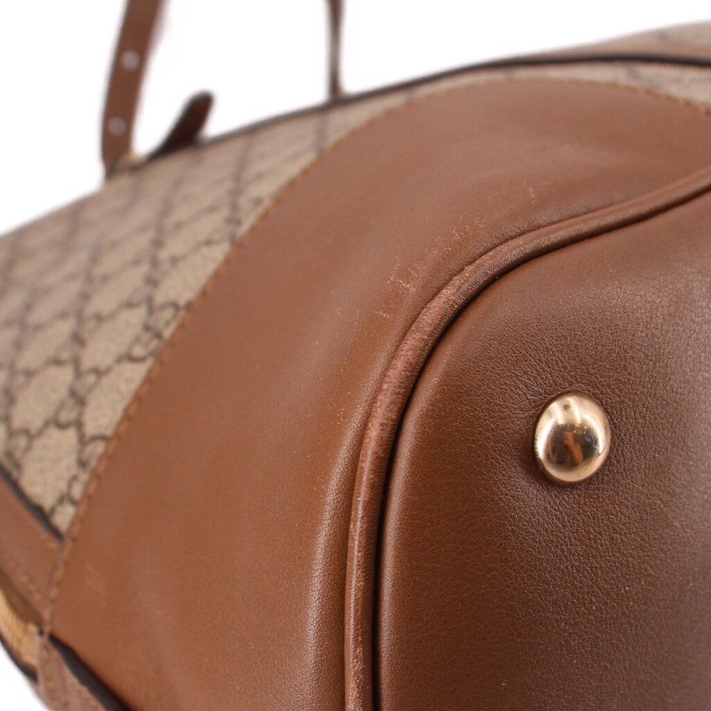 Brown leather corner detail with gold-tone rivet on dome handle bag