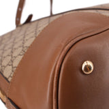 Brown leather corner detail with gold-tone rivet on dome handle bag