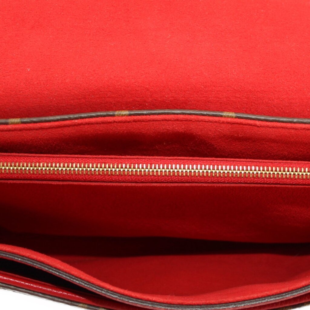Red fabric interior of crossbody bag with zipper opening and visible stitching