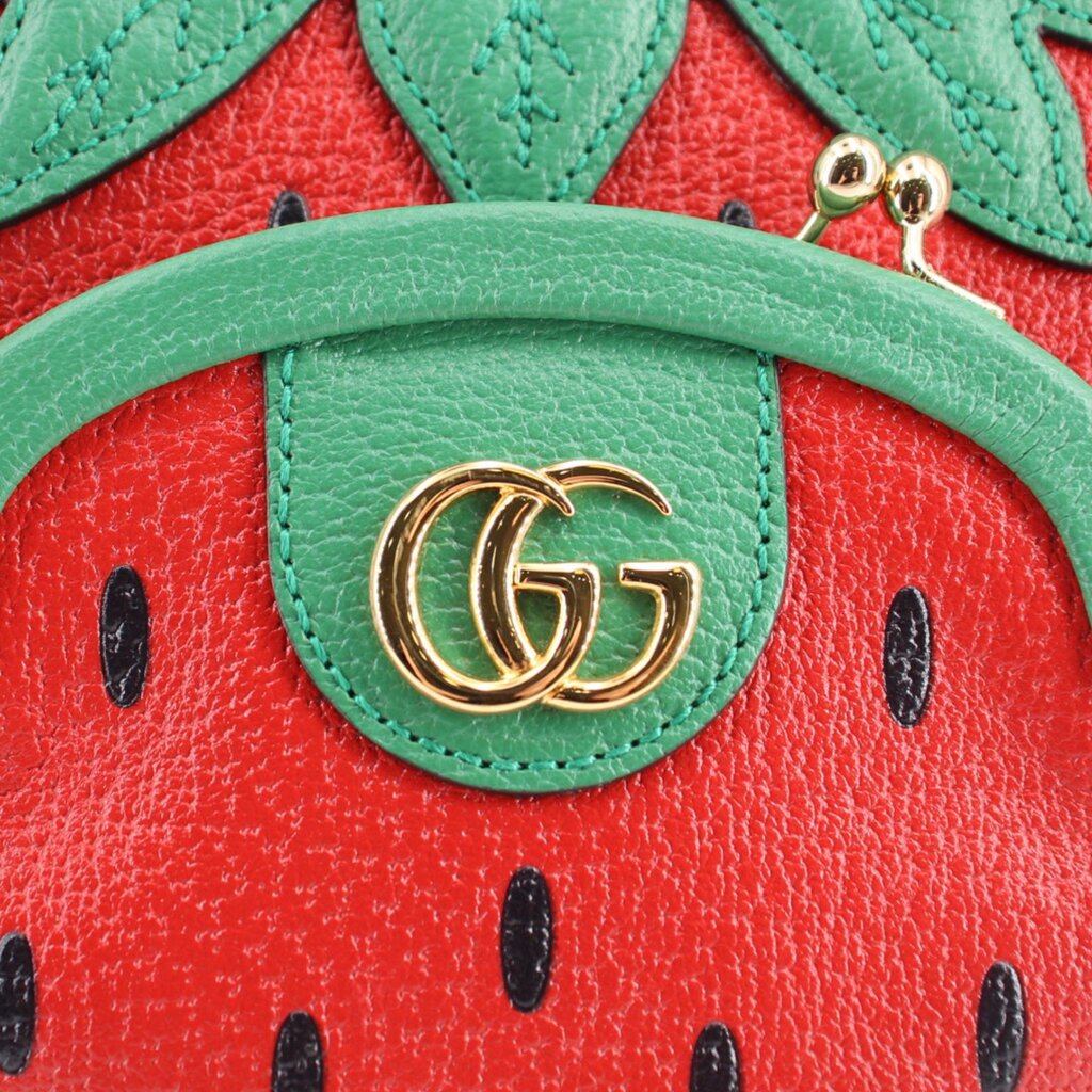 GUCCI strawberry crossbody bag close-up, gold GG logo on green patch over red