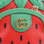 GUCCI strawberry crossbody bag close-up, gold GG logo on green patch over red