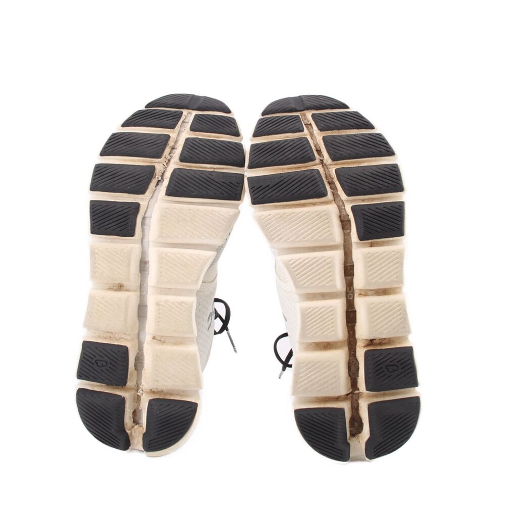 White ON Cloud sneaker outsoles with black tread blocks and grid-pattern cushioning