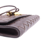 Close-up of chocolate woven leather flap corner with gold-tone clasp hardware