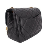 Black quilted mini crossbody bag side angle with flap stitching and gold chain