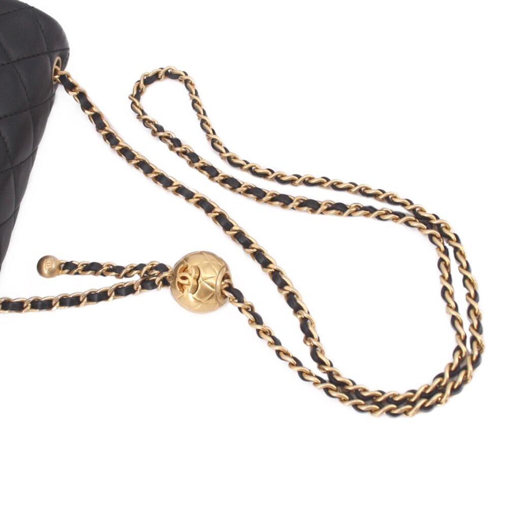 Gold-tone chain strap with clasp on black quilted mini crossbody bag