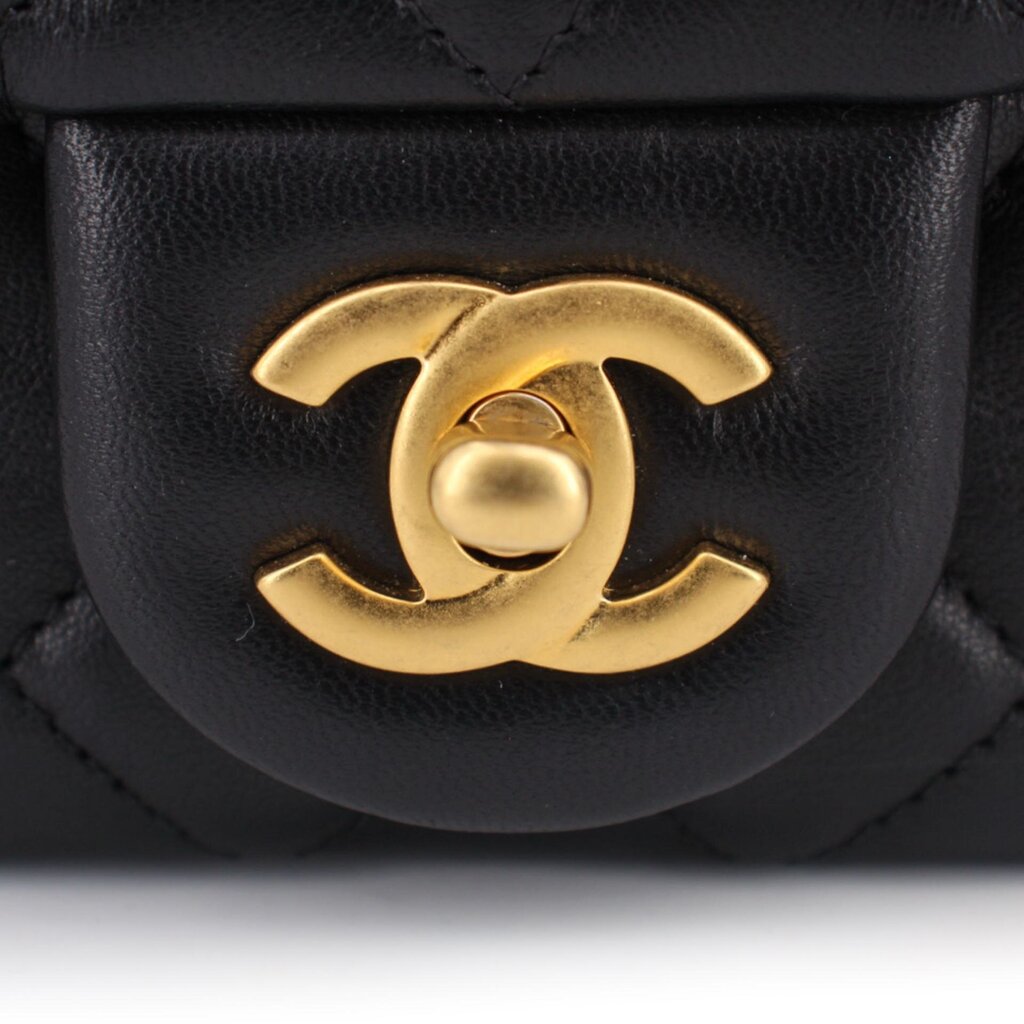 Gold CC turn-lock detail on black quilted mini crossbody bag flap