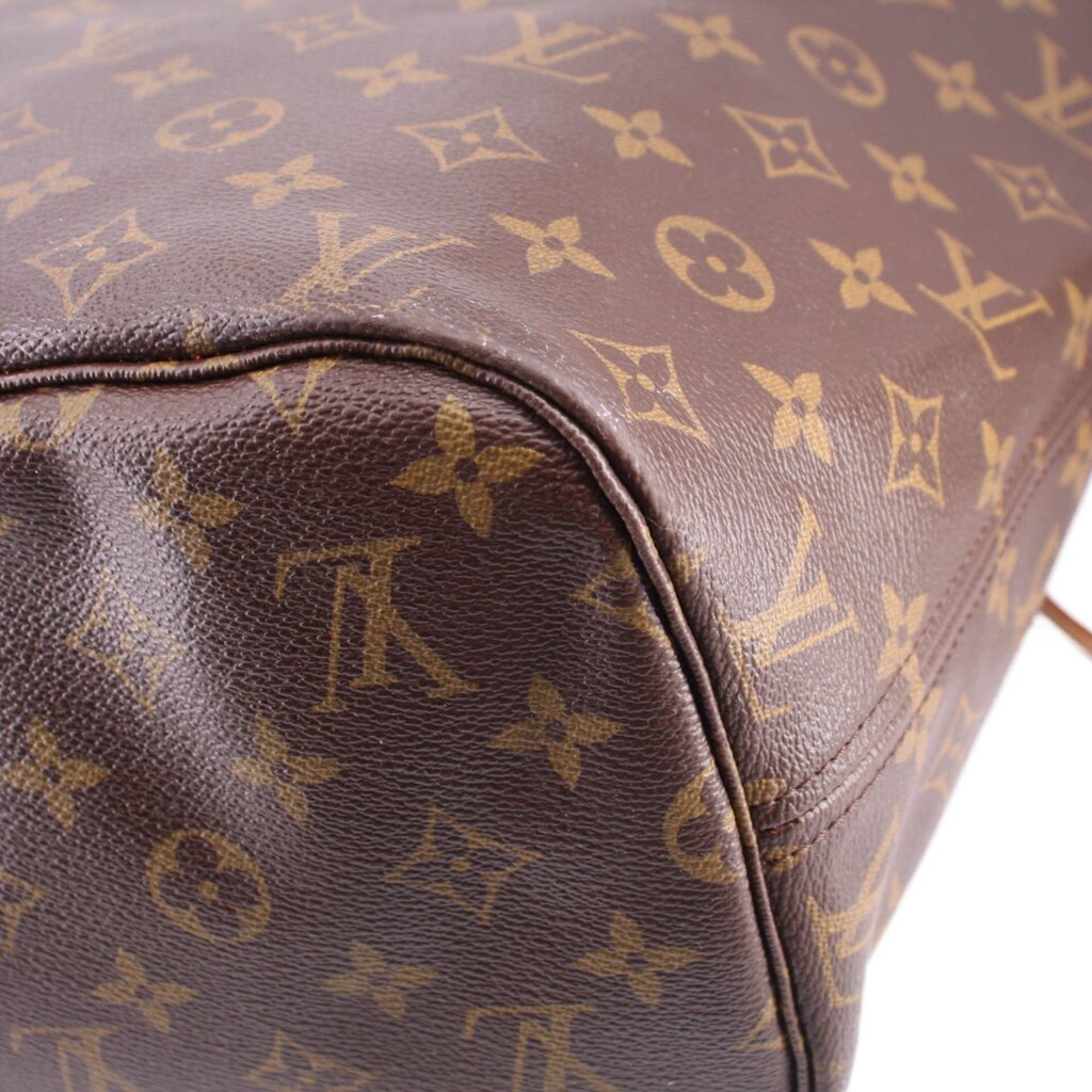 Close-up of monogram zip pouch corner with dark leather trim and stitched edge