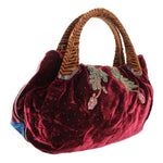 Maroon velvet mini bag with top handles and embroidered crest motifs along the front
