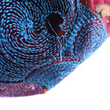 Close-up of blue embroidered beading swirl with purple and red accents