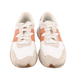 Pair of beige suede sneakers with orange stripes, white laces, and cushioned tongue