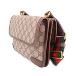GUCCI GG canvas crossbody bag angled view with front pocket and striped web strap