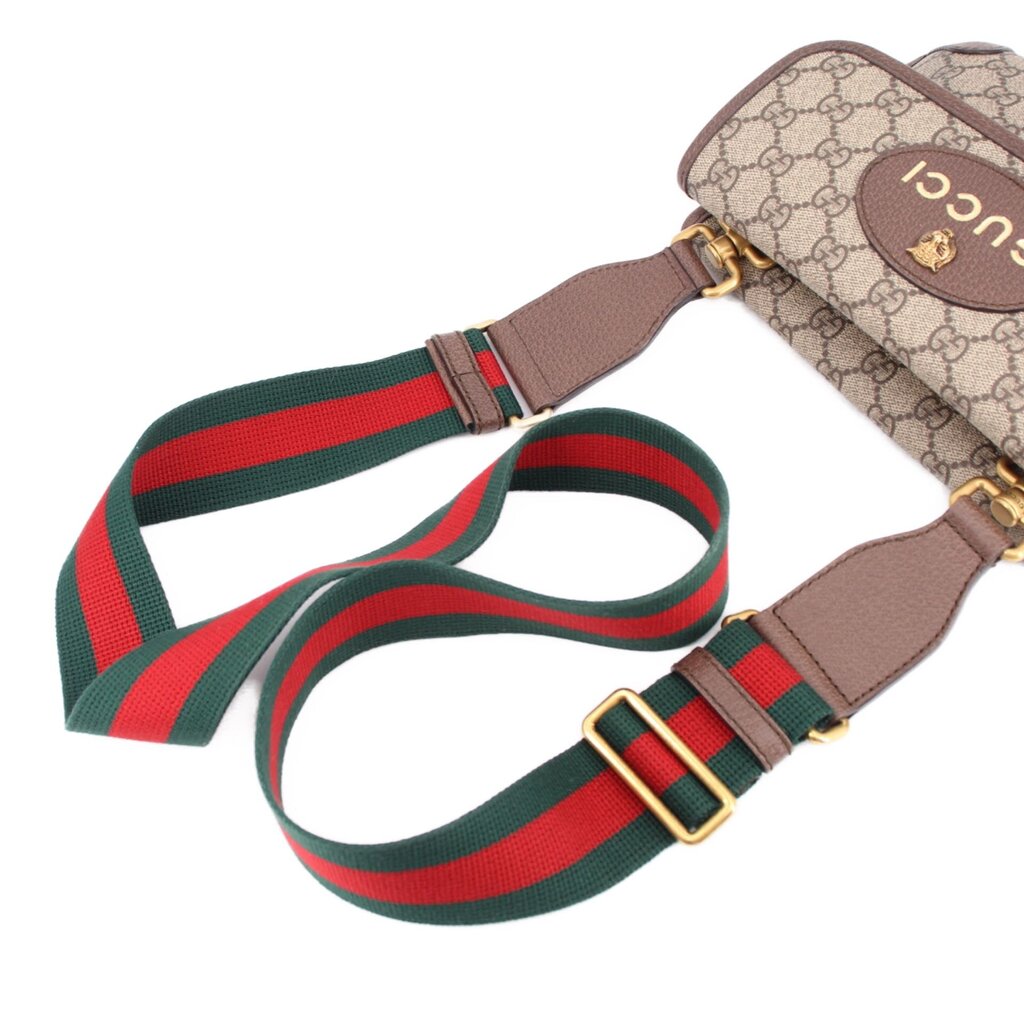 Striped green and red crossbody strap with gold-tone buckles and leather tabs