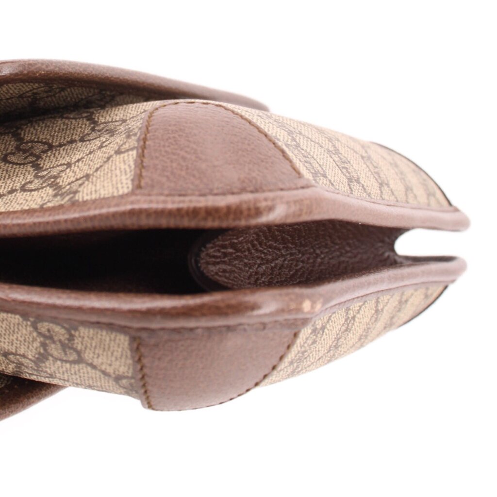 Brown leather and GG monogram crossbody bag close-up at side seam and flap