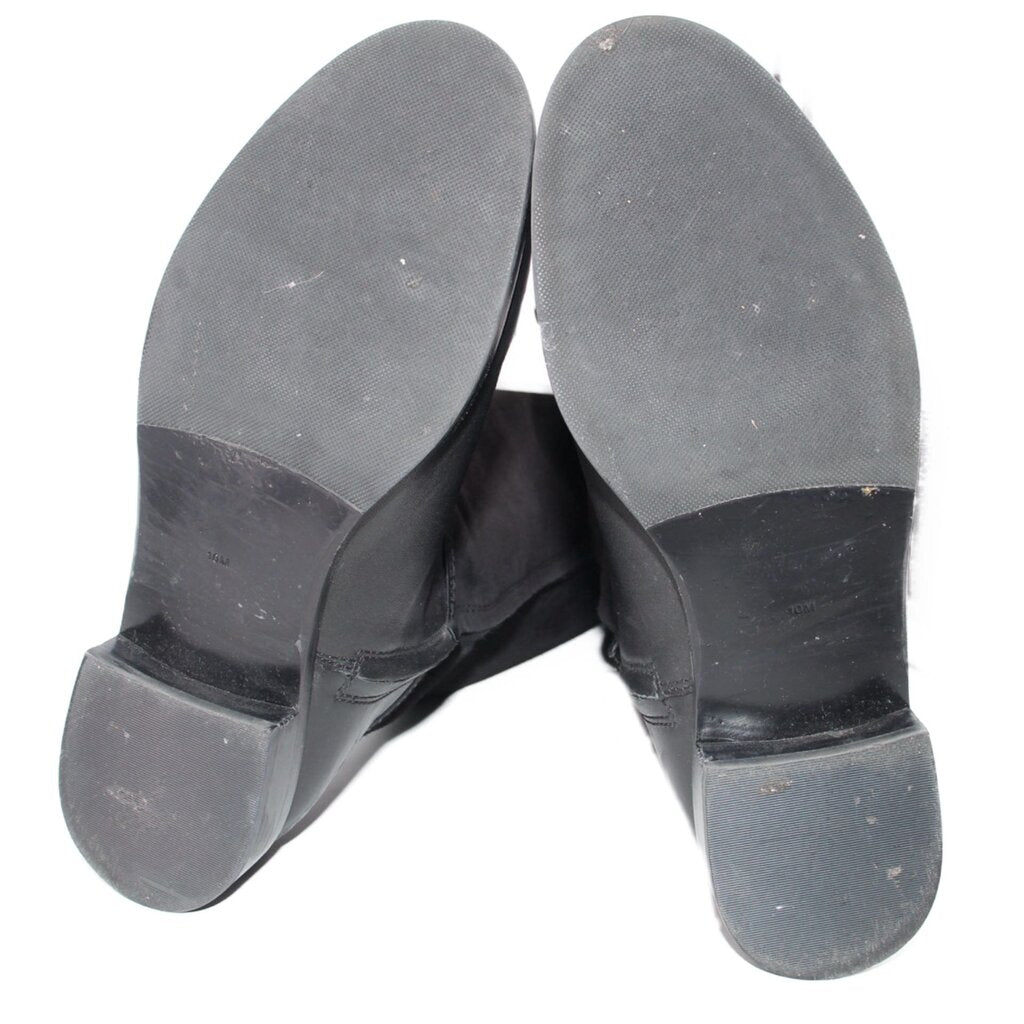 Bottom view of black boots showing rubber soles and heel tread