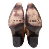 Tan suede cowboy boots showing branded heel counters and textured rubber soles