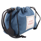 Denim blue drawstring pouch with black cords, front logo patch, and side leather trim