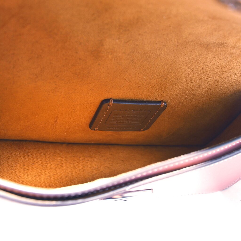 Tan fabric interior of rose small flap crossbody bag with embossed logo patch
