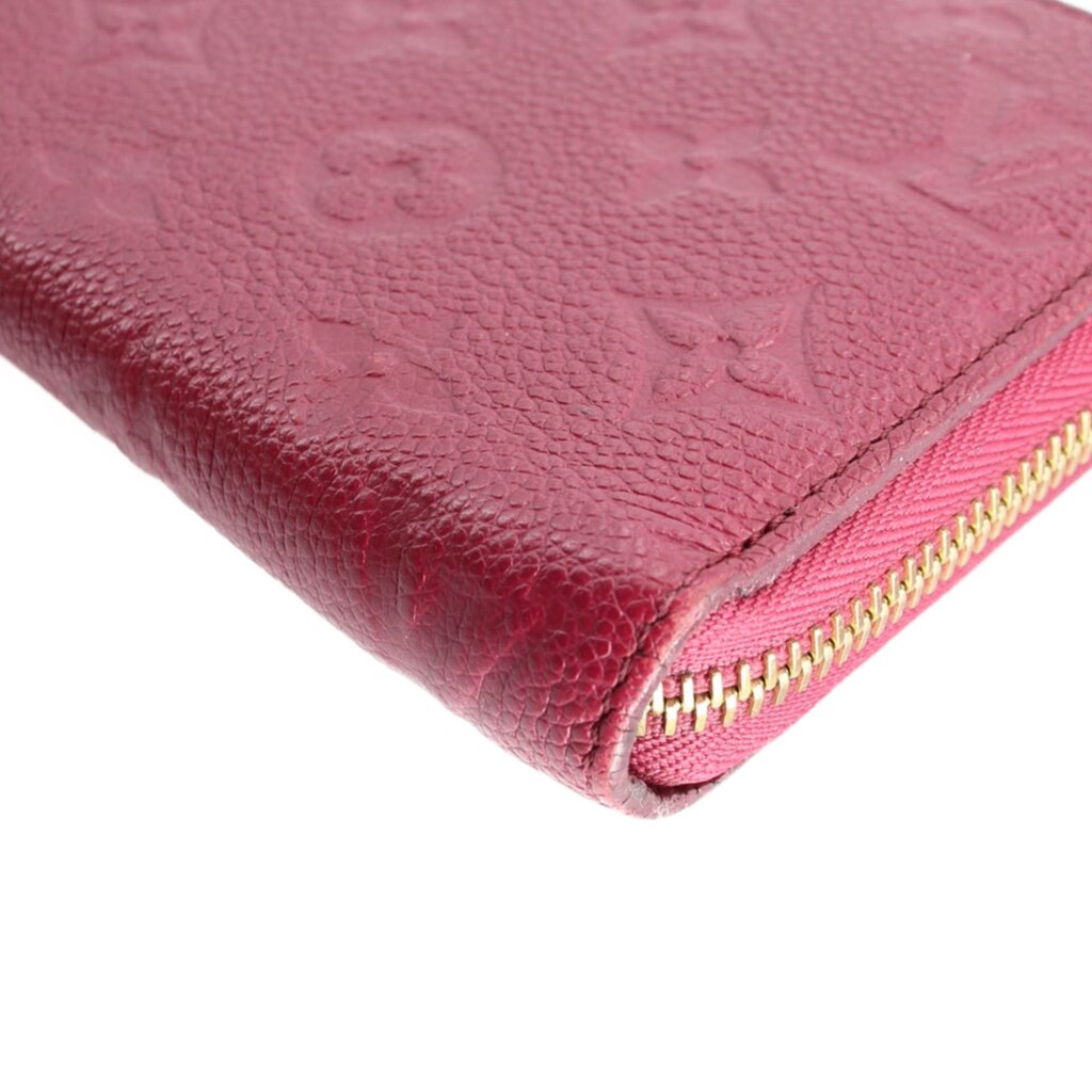 Gold-tone zipper close-up on burgundy empreinte leather zip wallet.