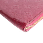 Gold-tone zipper close-up on burgundy empreinte leather zip wallet.