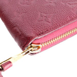 Zipper and leather edge close-up on burgundy empreinte wallet with gold hardware.