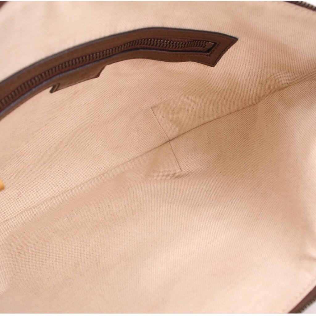 Beige fabric interior lining of a brown GG canvas shoulder bag with stitched edge