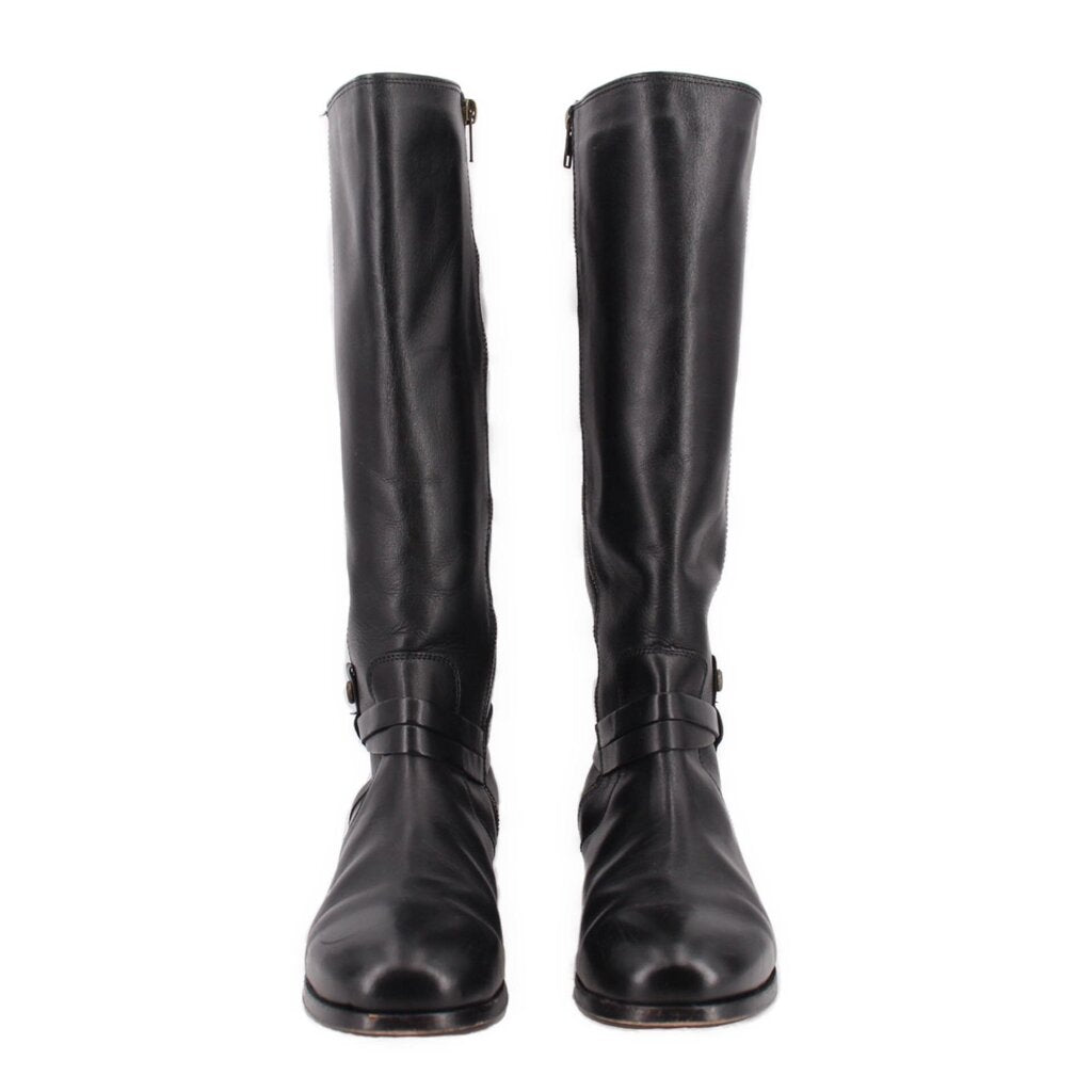 Pair of black leather tall boots with belted strap around lower shaft