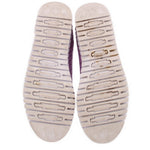 Shoe outsoles showing purple branding and grip tread on white platform bottoms