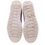 Shoe outsoles showing purple branding and grip tread on white platform bottoms