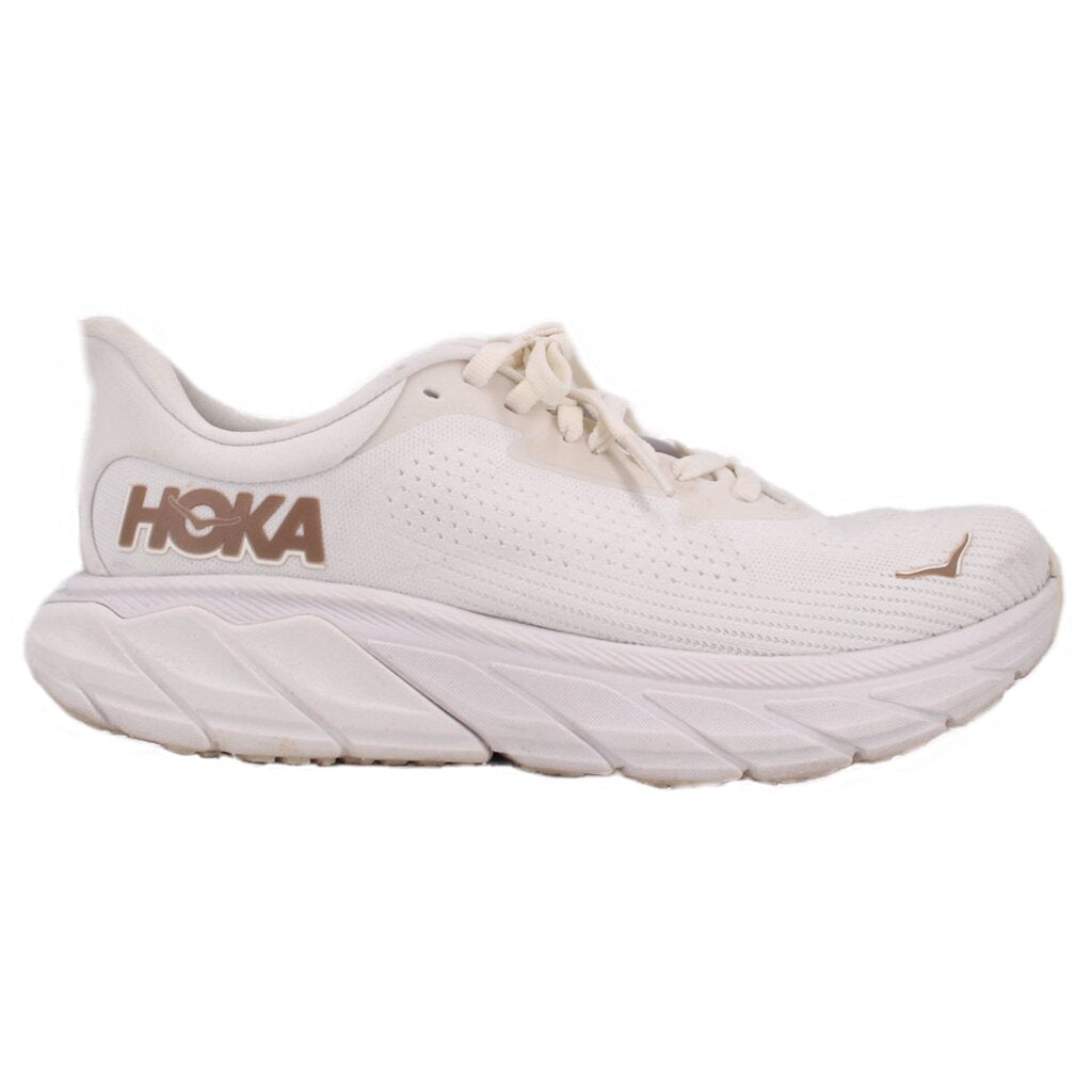 White lace-up running sneakers with HOKA logo on side and thick ribbed sole