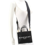 Black GIVENCHY mini G tote crossbody worn at side with adjustable strap