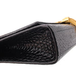 Close-up of black croc-embossed flap with gold-toned edging