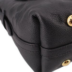 Close-up side of black monogram bag with pleated corner and gold-tone snap