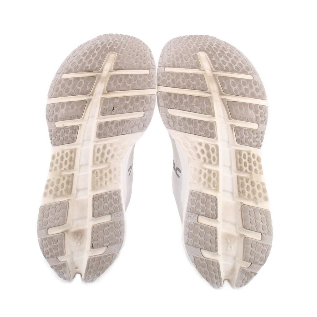 White sneaker outsoles with patterned tread and ON logo on heel area
