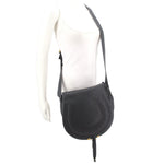 Black saddle crossbody bag worn with adjustable strap on a mannequin torso