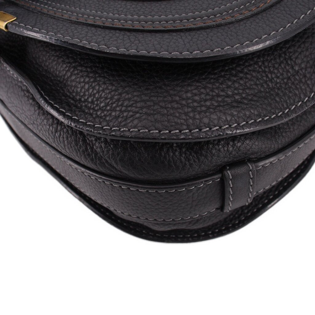 Black saddle crossbody bag close-up of stitched trim along the curved edge
