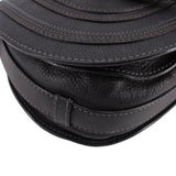Black saddle crossbody bag close-up of seam details and flap edge hardware
