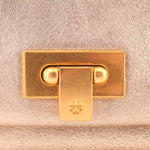 Gold-tone turn-lock clasp detail on tan foldover clutch.