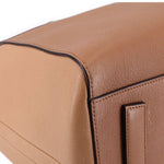 Brown leather tote bag side with rectangular tab and stitched seams