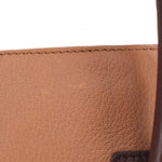 Brown leather bag edge close-up with textured grain and stitched border