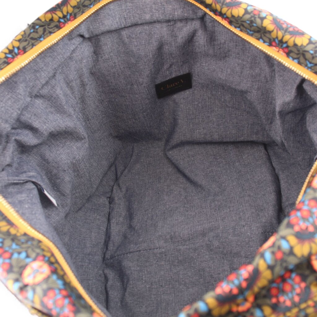 Gray fabric-lined interior of floral tote bag with small brand patch