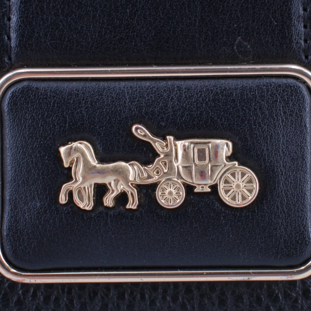 Front flap logo plaque with gold-tone horse-and-wagon emblem on black leather