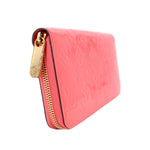 Coral patent zip wallet with gold-tone zipper and embossed monogram pattern