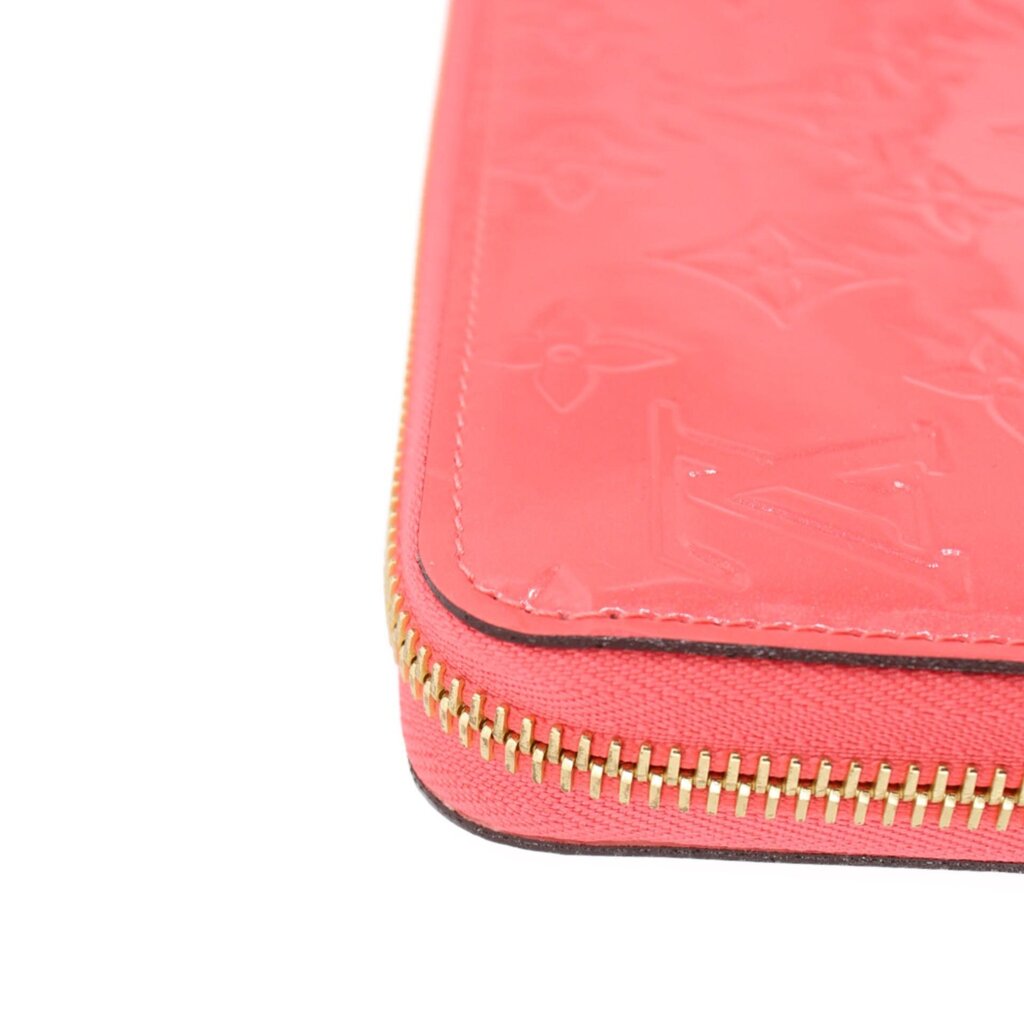 Coral zip wallet corner with gold zipper teeth and stitched edge detail