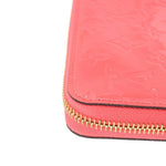 Coral zip wallet corner with gold zipper teeth and stitched edge detail