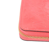 Coral zip wallet corner with gold zipper teeth and stitched edge detail