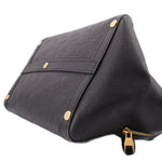 Black handle bag close-up with monogram front, strap seam, and gold corner hardware.