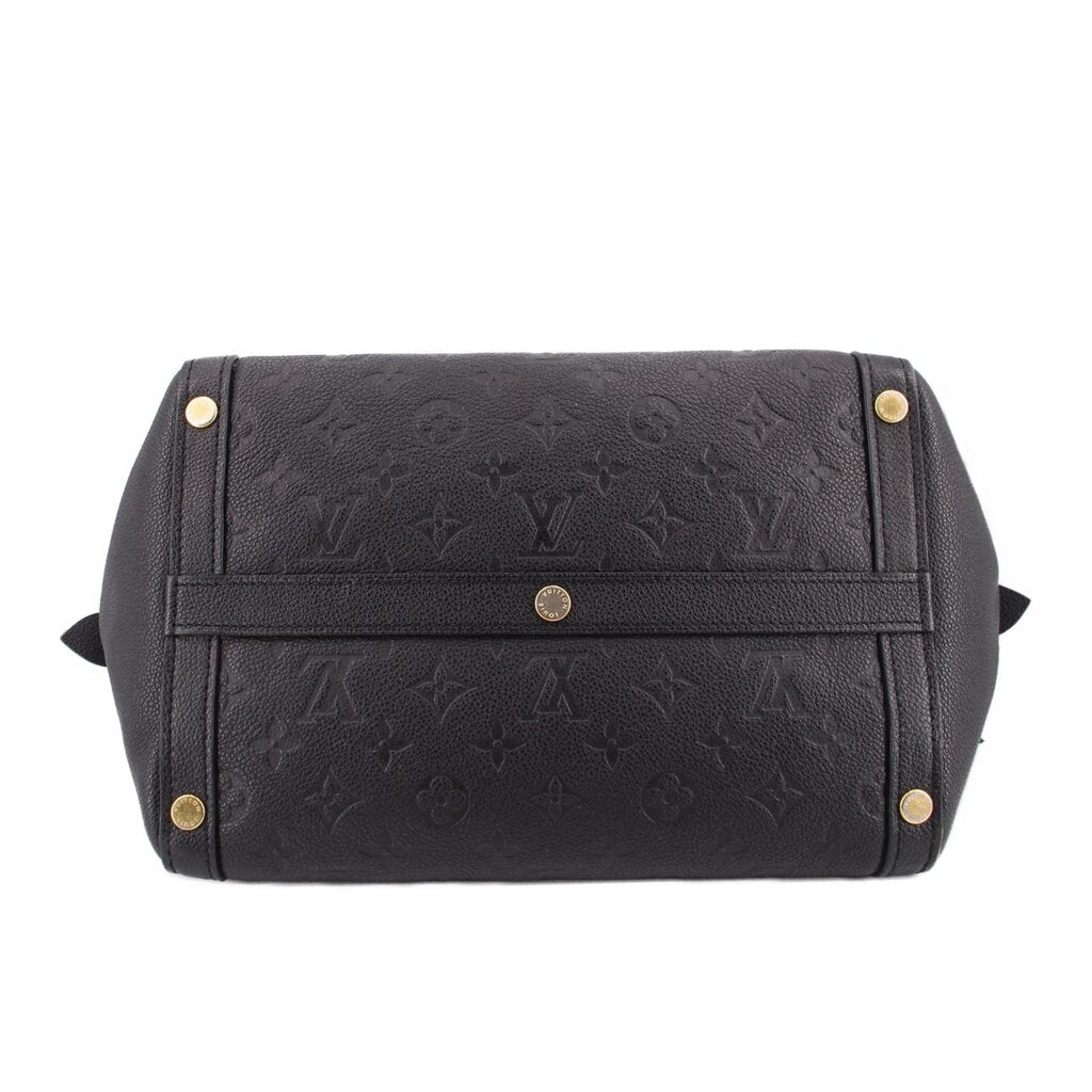 Black top-handle bag with centered strap detail, gold rivets, and embossed monogram.