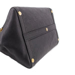 Black leather handle bag close-up of strap panel with gold rivets and monogram embossing.